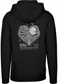 Felpa nera con cappuccio caratterizzata da un design grafico di un torace e una rosa, con testo bianco che recita "Impara ad amare il dolore" e altre frasi.