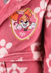 Pink fleece fabric with white paw prints and a patch of a smiling cartoon dog with pink goggles and raised paws.