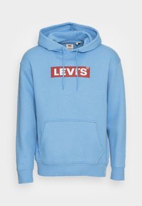 Ljusblå hoodie tillverkad av bomullsblandat tyg. Har en framficka, dragsko i huvan och en röd rektangulär "LEVI'S"-logotyp på bröstet.