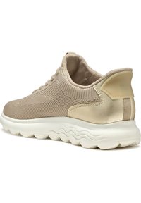 Sneaker beige con una toma a maglia testurizzata, dettagli metallici e una suola bianca spessa con un motivo a onda. Marchio Geox sul tallone.