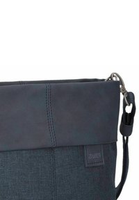 Bolso de hombro azul oscuro con tejido suave y una tapa de cuero liso, con un cierre de metal y un parche con el logotipo en el lateral.