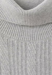 Grijze gebreide coltrui met geribbelde textuur, verticale strepen en kabelgebreide accenten voor extra detail en diepte.