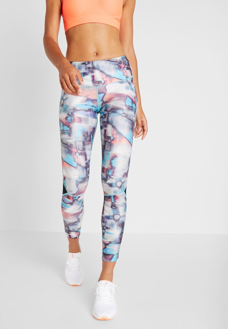 Legíny s abstraktním akvarelovým vzorem v modré, růžové a šedé barvě. Vyrobeno z elastického materiálu s přiléhavým střihem. Doplněno o bílé sneakers.