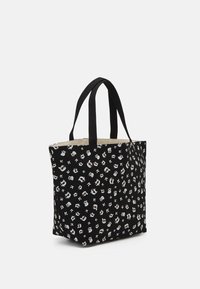 Musta puuvillainen kangaskassi, jossa on satunnainen valkoisen ja harmaan kuvio, tukevat mustat kahvat ja tilava sisätila vaalealla vuorauksella.