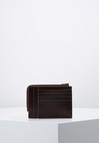 Cartera de cuero marrón con cierre de cremallera, que cuenta con múltiples ranuras para tarjetas y acentos de costura azul en la parte frontal. Textura suave, forma rectangular.