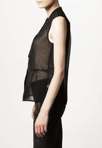 Blusa nera trasparente senza maniche con un alto colletto e sottili variazioni di texture. Vestibilità ampia con design a strati, tessuto parzialmente trasparente.