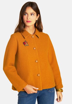 Orange Wolle-Mischung Jacke mit kragenförmigem Ausschnitt, fünf Knöpfen und einem dekorativen Patch des Eiffelturms und eines Herzens auf der linken Seite.