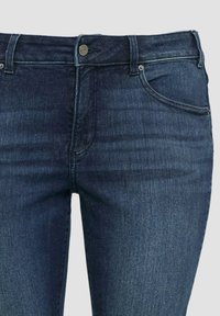 Dunkelblaue Denim-Jeans mit einem klassischen Fünf-Taschen-Design, Metallknopfverschluss und subtilen Strukturvariationen.