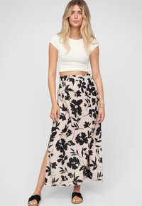 Maxihame vaaleanpunaisena mustilla kukkakuosisilla, jossa on joustava vyötärö ja sivuaukko. Yhdistettynä valkoiseen crop top -paitaan ja sandaaleihin.
