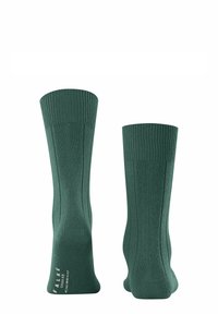 Calcetines de color verde oscuro, hechos de una mezcla de algodón, con textura acanalada, puños anchos y un acabado suave con un branding mínimo en el lateral.