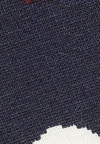 Tela de color navy con un tejido texturizado que presenta un elemento de diseño blanco a lo largo del borde inferior. No se observan patrones prominentes ni hardware visible.