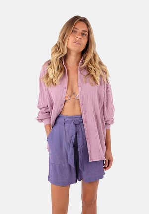 Chemise en coton lilas à bouton, associée à un short violet clair taille haute avec un cordon à la taille et deux poches avant.