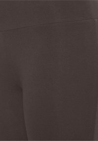 Svarta leggings tillverkade av mjukt, stretchy tyg. Har en hög midja med en sömlös design och en subtil, matt yta.