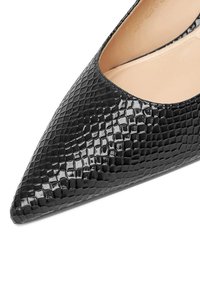 Melnas sašaurinātas purngaliem kurpes, kas izgatavotas no spīdīga teksturēta materiāla ar reptīliju ādas rakstu un gludu iekšējo oderi.