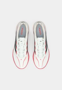 Λευκά αθλητικά παπούτσια με μαύρες και κόκκινες λεπτομέρειες, με στρογγυλεμένη μύτη, λεία υφή και εμφανές λογότυπο "COPA" στις εσωτερικές σόλες.