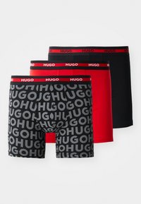 Dreierpack Boxer-Shorts: eine schwarze, eine einfarbige rote und eine mit schwarzem/rotem, sich wiederholendem "HUGO"-Logo. Weicher Baumwollmix, elastische Bündchen.