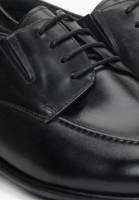 Czarne skórzane buty formalne z gładkim wykończeniem, sznurowanym fasonem i subtelnymi detalami przeszyć wzdłuż krawędzi.