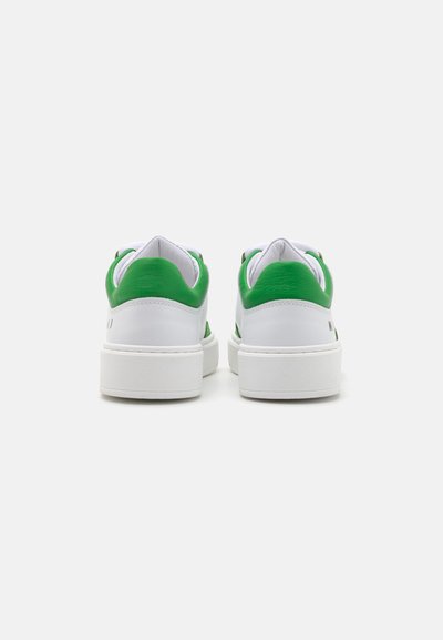 Vita sneakers med gröna accenter, med en slät läderöverdel, vadderade kragar och en texturerad gummisula. Bakview visar rena linjer.