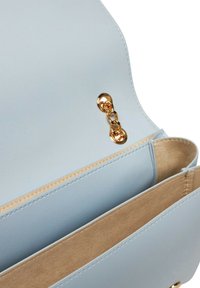 Interno di una borsa in pelle azzurro chiaro con una texture liscia, dotato di una catena dorata come hardware e di un rivestimento in suede sabbia. Sono visibili due scomparti.