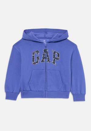 Felpa blu con zip e tasca frontale, caratterizzata dal logo "GAP" in un motivo floreale scuro. Realizzata in tessuto morbido con polsini elasticizzati.