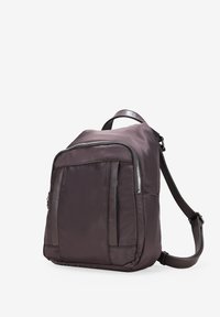 Zaino in nylon viola scuro con una texture liscia, dotato di un compartimento principale con zip e due tasche laterali con zip, spallacci in pelle regolabili.