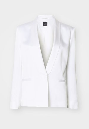 Bílý přizpůsobený blazer s saténovým povrchem, šálovým límcem a předními kapsami na klopu. Má strukturované ramena a dlouhé rukávy.