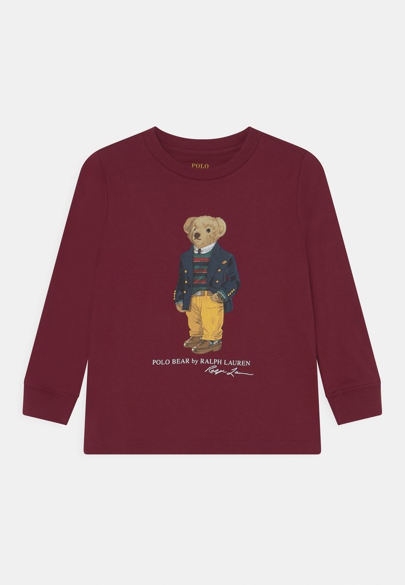 T-shirt à manches longues bordeaux avec une illustration d'un ours portant un blazer bleu, une chemise rayée et un pantalon jaune, avec un logo brodé en dessous.