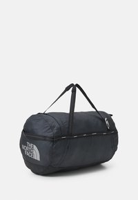 Svart duffelväska gjord av slitstarkt tyg, med dubbla handtag, dragkedjestängning och en stor logotyptryck på ena sidan.