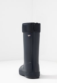 Botte de pluie en caoutchouc noir avec un dessus rembourré et texturé ; arbore le nom de la marque "igor" sur le côté ; finition lisse et semelle durable.
