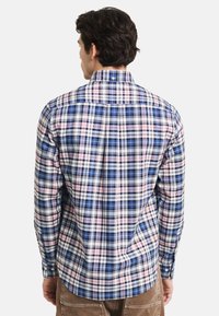 Karierte Bluse mit blauem, rosa und weißem Karomuster. Button-down-Kragen und lange Ärmel mit lockerer Passform und Rückenschlitz.