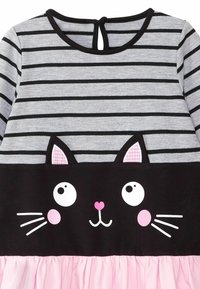 Randig grå långärmad klänning med design av en svart katt, med rosa detaljer, rund halsringning, rynkad rosa kjol och knäppning på baksidan.