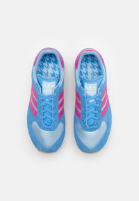 Adidas sneakers featuring a light blue suede upper, pink stripes, and a light blue houndstooth insole. Rounded toe, rubber sole.