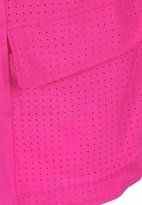 Helles pinkes Stoffmaterial mit kleinen Lochungen, ausgestattet mit einer Klappentasche. Glatte Textur und ein lässiges Design, das für verschiedene Stile geeignet ist.