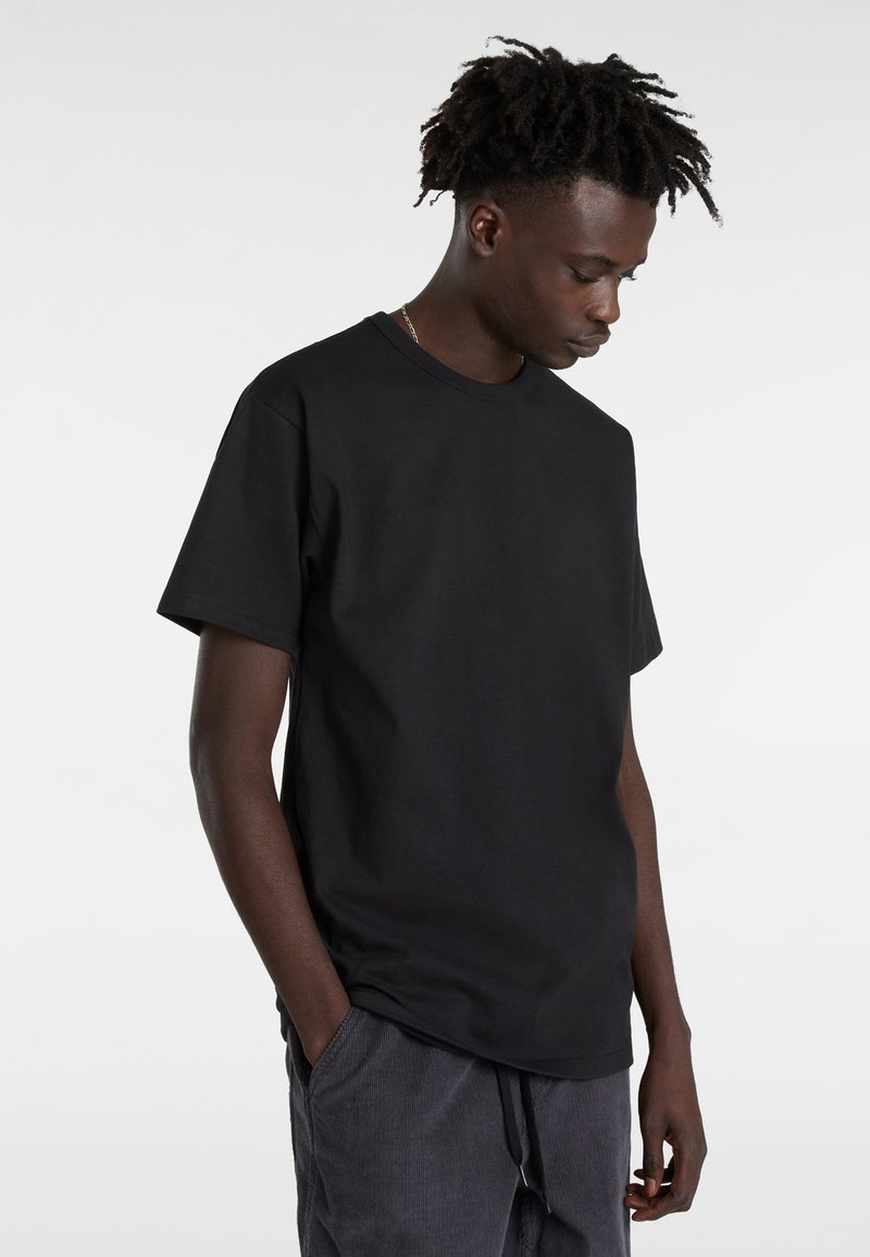 T-shirt noir à manches courtes en coton avec un col rond, offrant une coupe décontractée et une texture lisse. Design simple sans motifs.