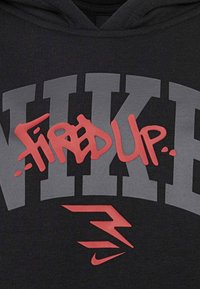 Felpa nera con cappuccio caratterizzata da grande testo grigio "NIKE" e un evidente grafica rossa "FIRED UP". Include un piccolo logo Nike rosso in basso.
