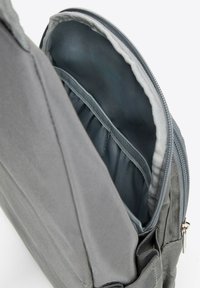 Szary plecak z tkaniny z zamykanym na suwak głównym schowkiem, wewnętrznymi kieszeniami na organizację i lekkim, teksturowanym designem.