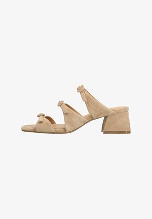 Sandales à talons blocs en suédine beige avec trois brides présentant des détails en boucle et une conception à bout arrondi. Texture douce avec un look minimaliste.