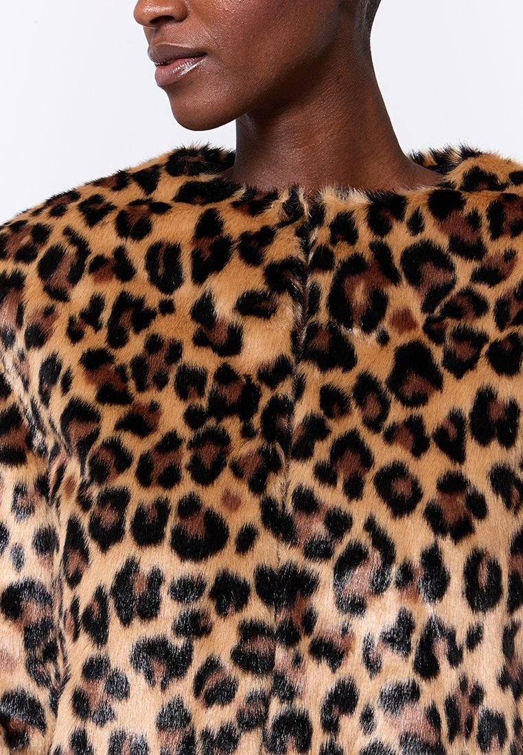 Abrigo de piel sintética con estampado de leopardo y cuello redondeado, que presenta diversas tonalidades de marrón y manchas negras sobre un fondo beige.