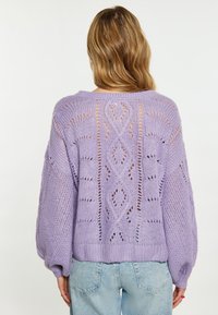 Lila gestrickter Pullover mit offenen Rauten- und Kreis-Mustern, gerippten Bündchen und Saum, zeichnet sich durch einen lockeren Schnitt und strukturierte Garne aus.