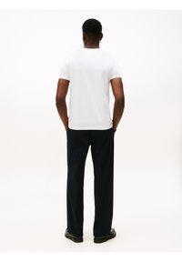 Camiseta blanca de manga corta, diseño ajustado, combinada con pantalones rectos azul marino oscuro. Líneas limpias, construcción sin costuras y sin logotipos visibles.