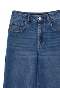 Jeans in denim blu con un design classico, caratterizzati da una chiusura con bottoni, cinque tasche e un leggero effetto sbiadito. Le cuciture sono di un colore beige a contrasto.