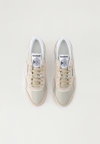 Reebok teniske z bež samta in zgornjim delom iz zelene tkanine, okrogli vezalke, oblazinjen jezik ter črn logotip na jeziku z obliko zvezde.