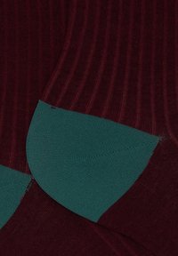 Tessuto a coste color bordeaux con un accento liscio in teal sul tallone. Presenta un motivo testurizzato e un design a blocchi di colore a contrasto.