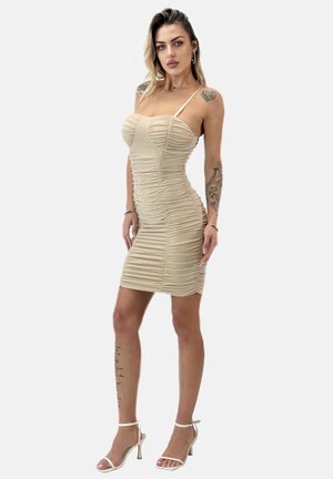 Beige, gerafftes Bodycon-Kleid mit Spaghetti-Trägern, das ein tailliertes Design, strukturierter Stoff und eine Länge bis zur Mitte des Oberschenkels aufweist. Getragen mit klaren High Heels.