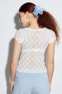 Witte kanten top met korte mouwen, voorzien van een delicate bloemenontwerp en blauwe accenten langs de halslijn en zoom. Zachte textuur en aansluitende pasvorm.