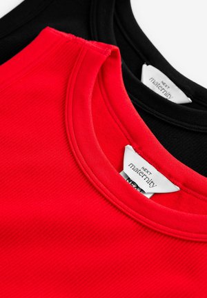 Rote und schwarze Umstandstopps, mit geripptem Stoff und Rundhalsausschnitten. Sichtbare Etiketten mit "Next Maternity" Branding.