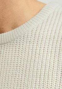 Jasnoszary sweter dziany z prążkowanym okrągłym dekoltem, z teksturowanym wzorem i miękkim materiałem, podkreślający otwartą strukturę tkaniny.