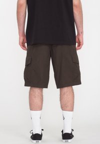 Brune cargo shorts lavet af bomuld, med sidelommer, syet detaljering og en almindelig pasform. Bæres med hvide sokker og sorte sko.