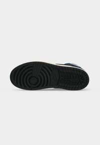 Μαύρη λαστιχένια σόλα αθλητικού Nike, φαίνεται από κάτω, με κυκλικά και ορθογώνια μοτίβα πέλματος και το λογότυπο της Nike στο κέντρο.