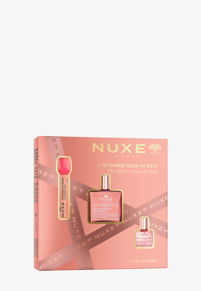 Zestaw prezentowy NUXE zawiera różowe pudełko z złotymi akcentami, w którym znajduje się butelka różowego oleju, mniejszy olej oraz serum do ust z jaskraworóżowym aplikatorem.